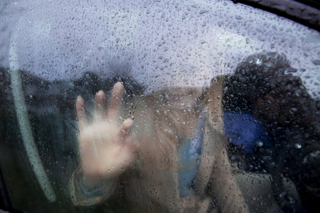 Woman looking outside car window while it rains
