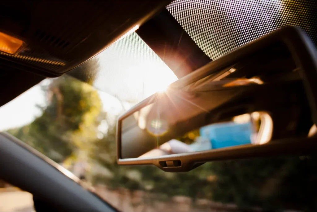 Sunlight reflecting on a rearview mirror inside a car.