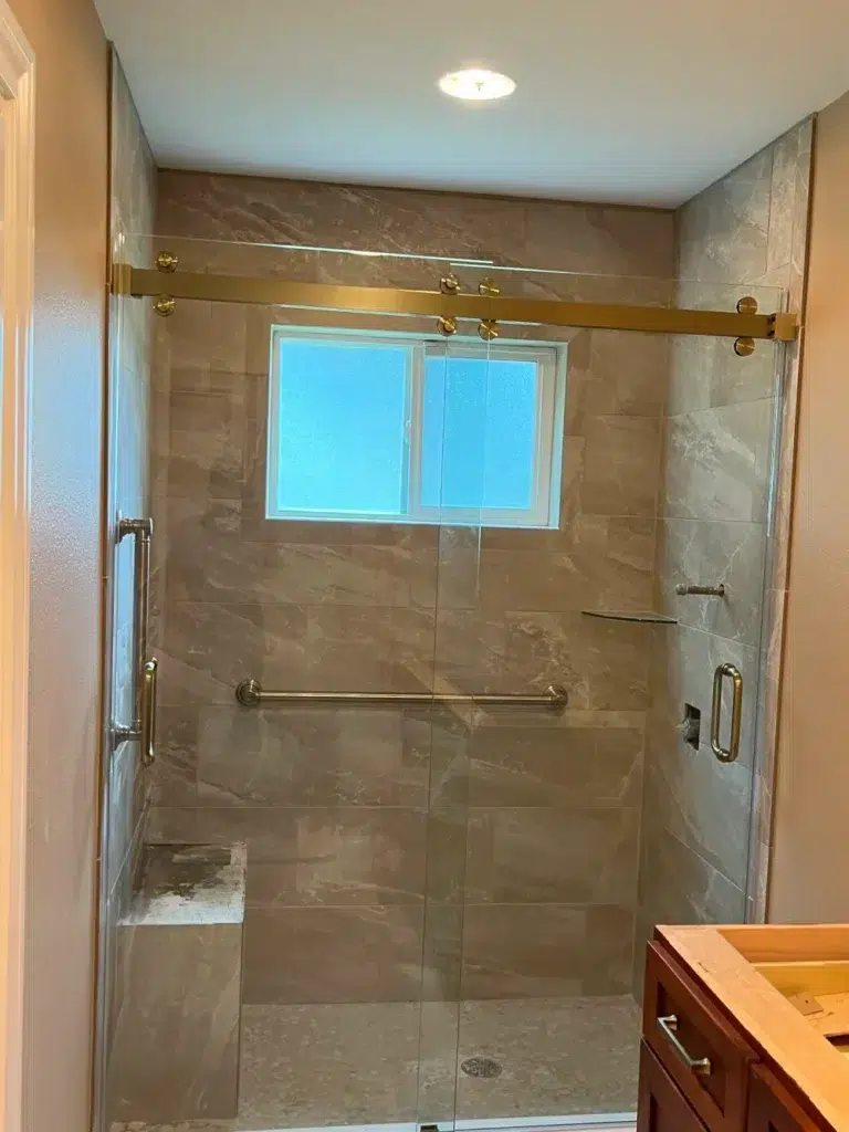 Shower with glass doors and gold hardware.