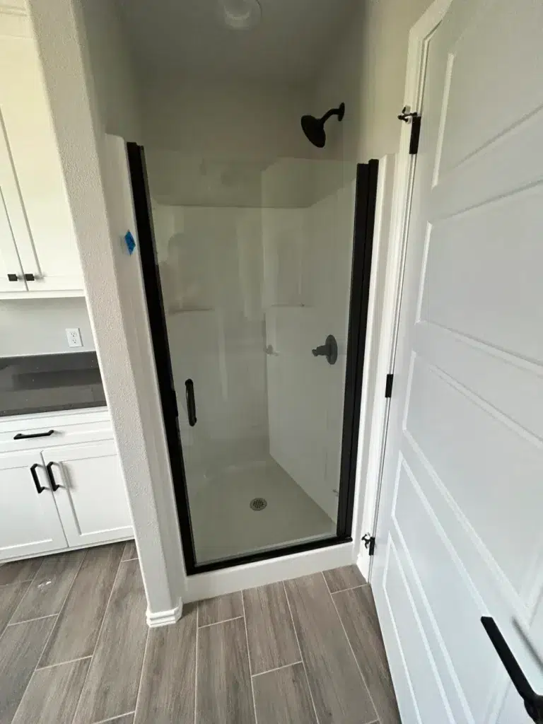 Compact shower with black-framed glass door enclosure.