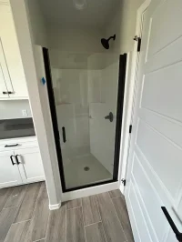 Compact shower with black-framed glass door enclosure.